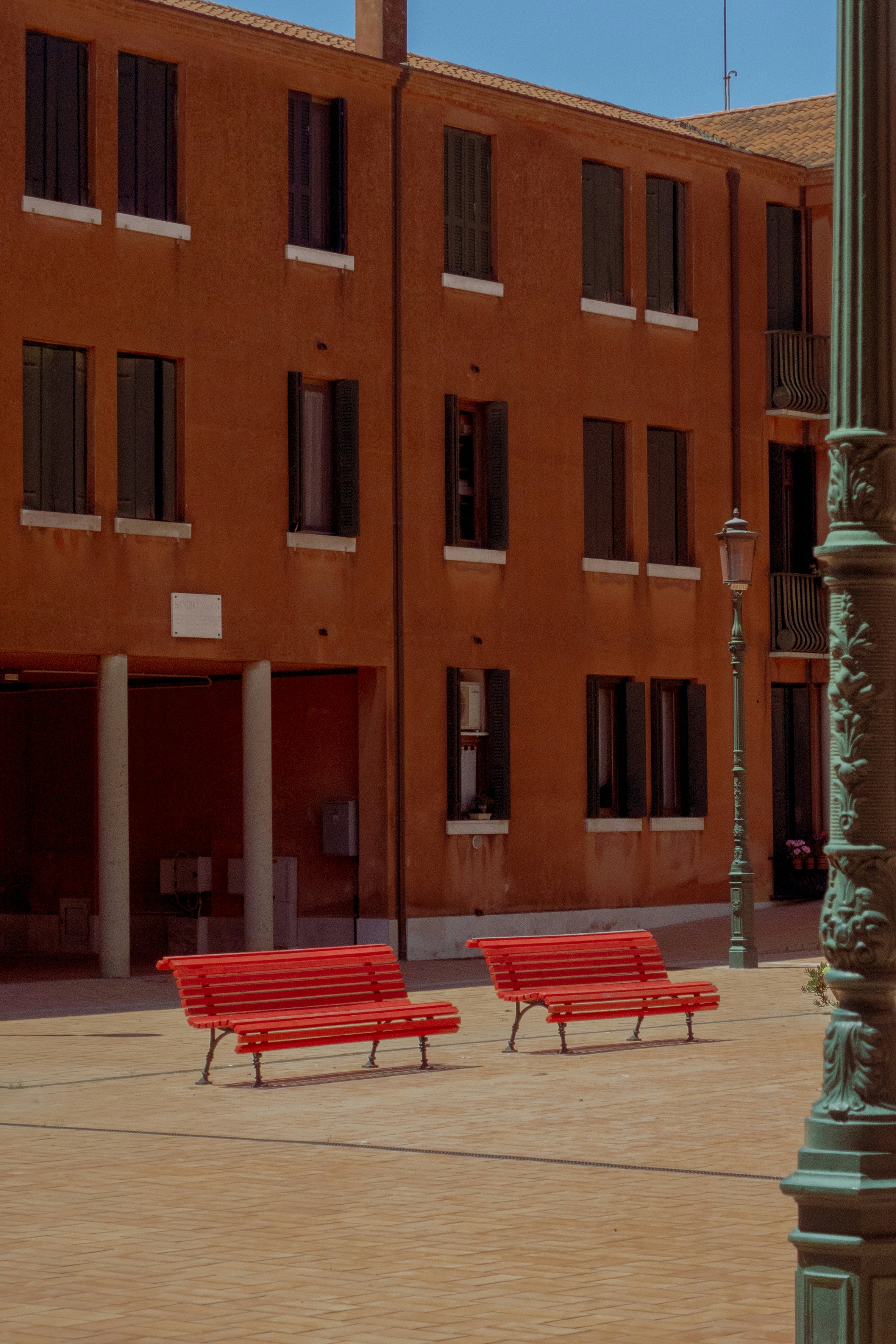 quelques bancs rouges assis devant un grand bâtiment