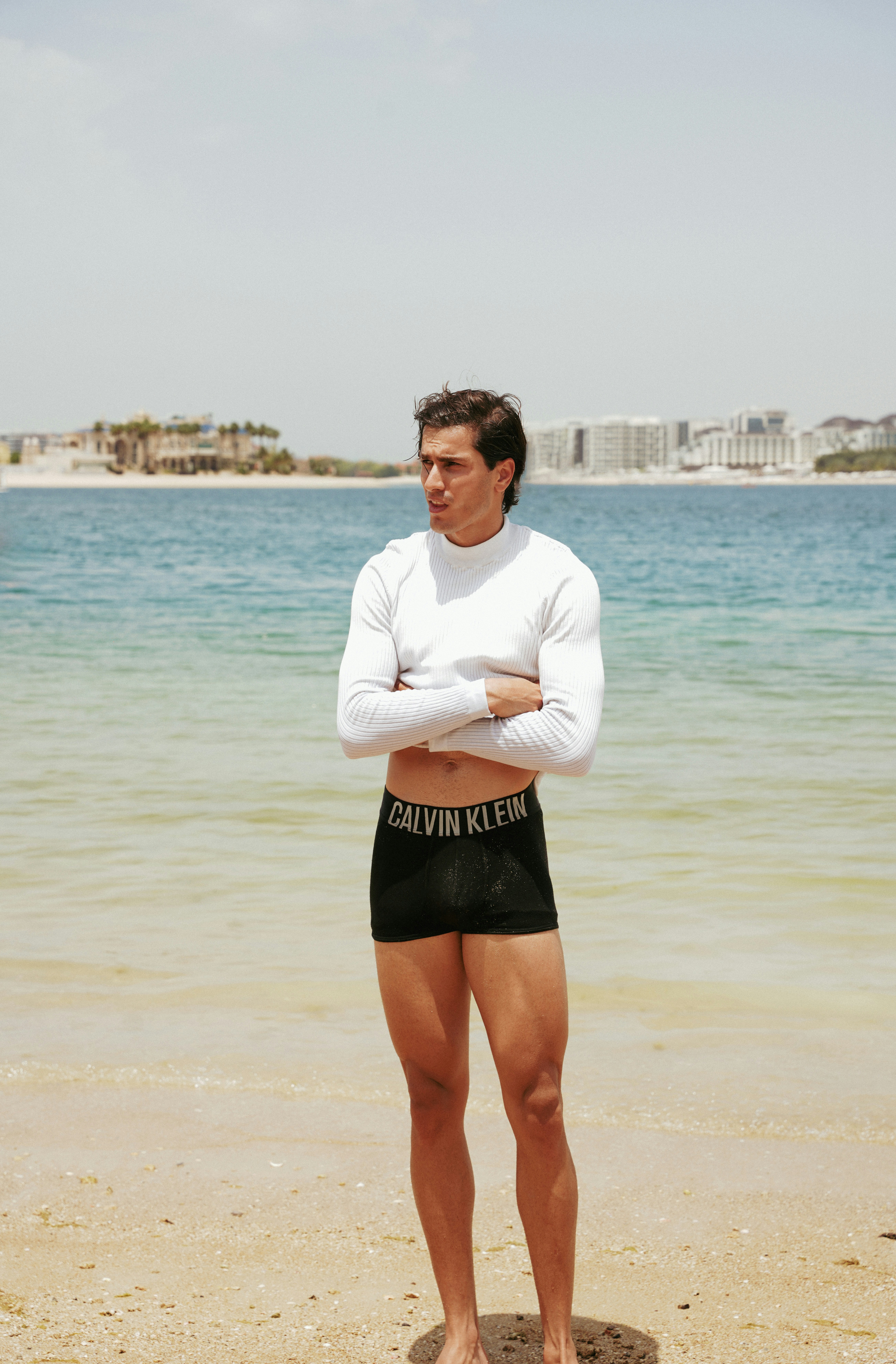 A man standing on top of a sandy beach next to the ocean photo – Free ...
