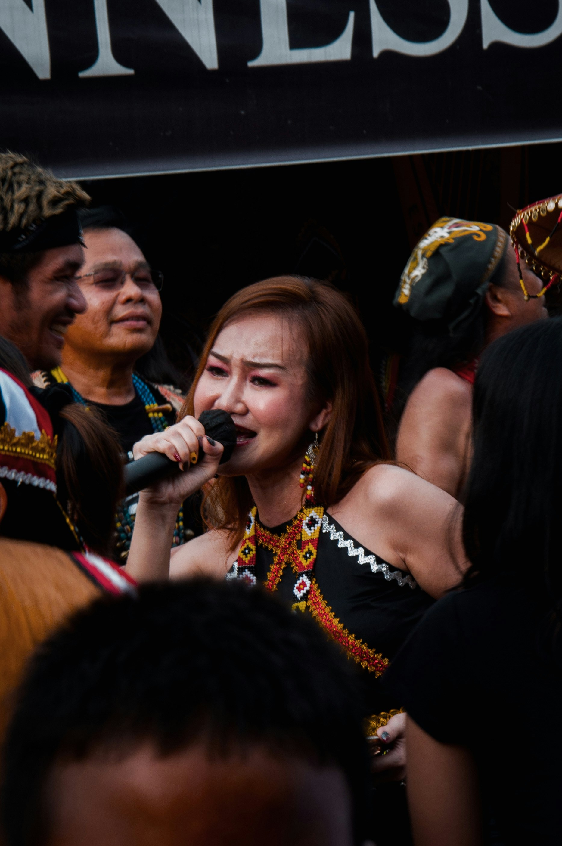 a woman singing into a microphone surrounded by people