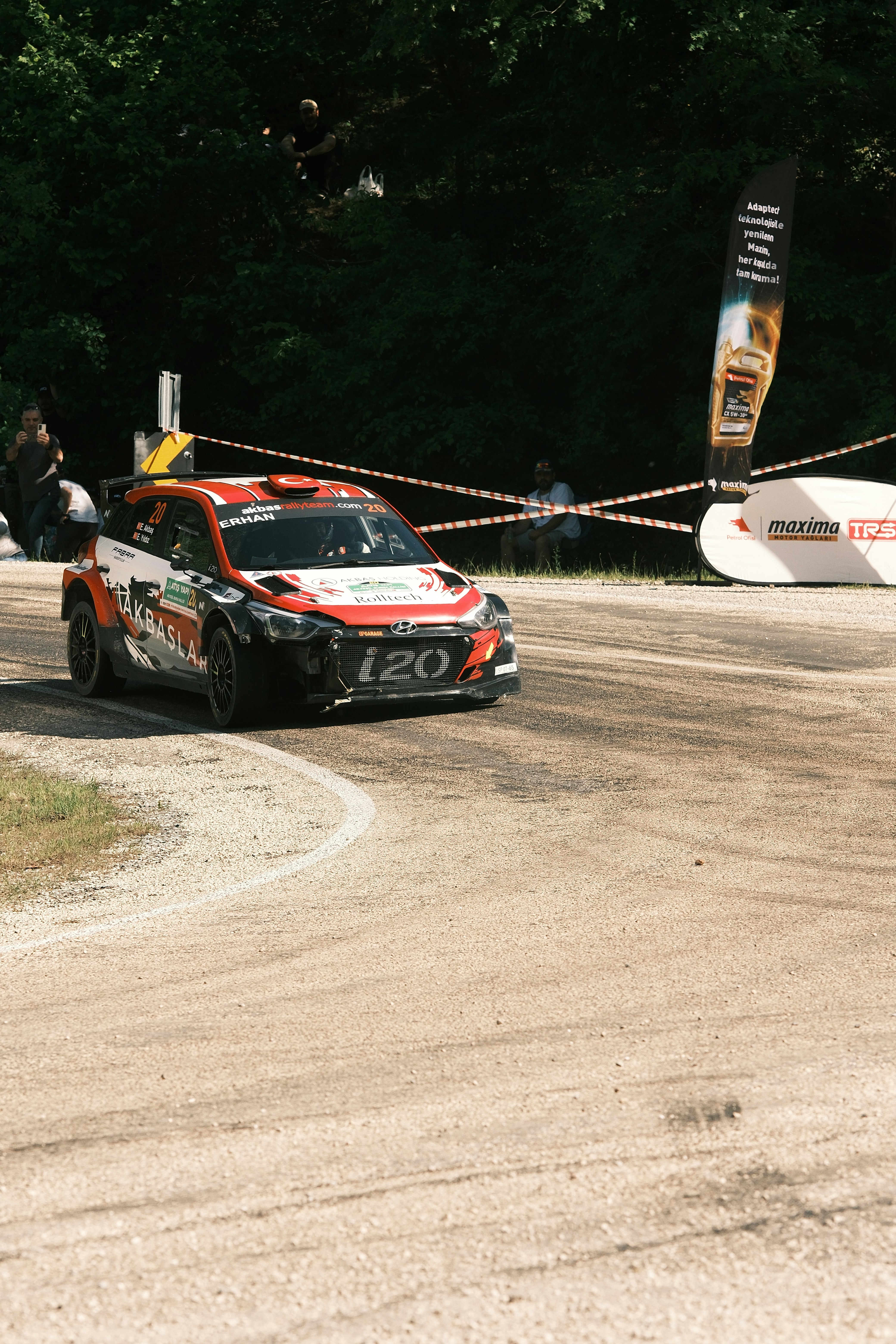 a car driving down a race track with a person standing next to it