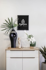 a black vase sitting on top of a white dresser