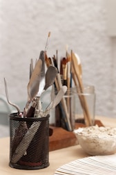 a cup filled with utensils on top of a wooden table
