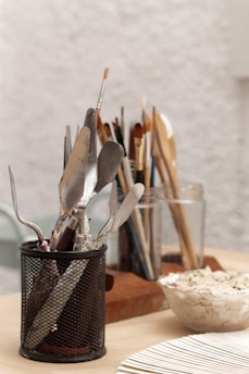 a cup filled with utensils on top of a wooden table