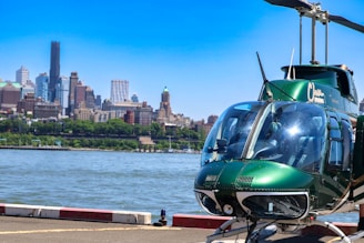 a green helicopter sitting on top of an airport tarmac