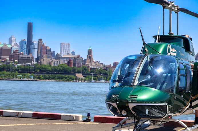 a green helicopter sitting on top of an airport tarmac