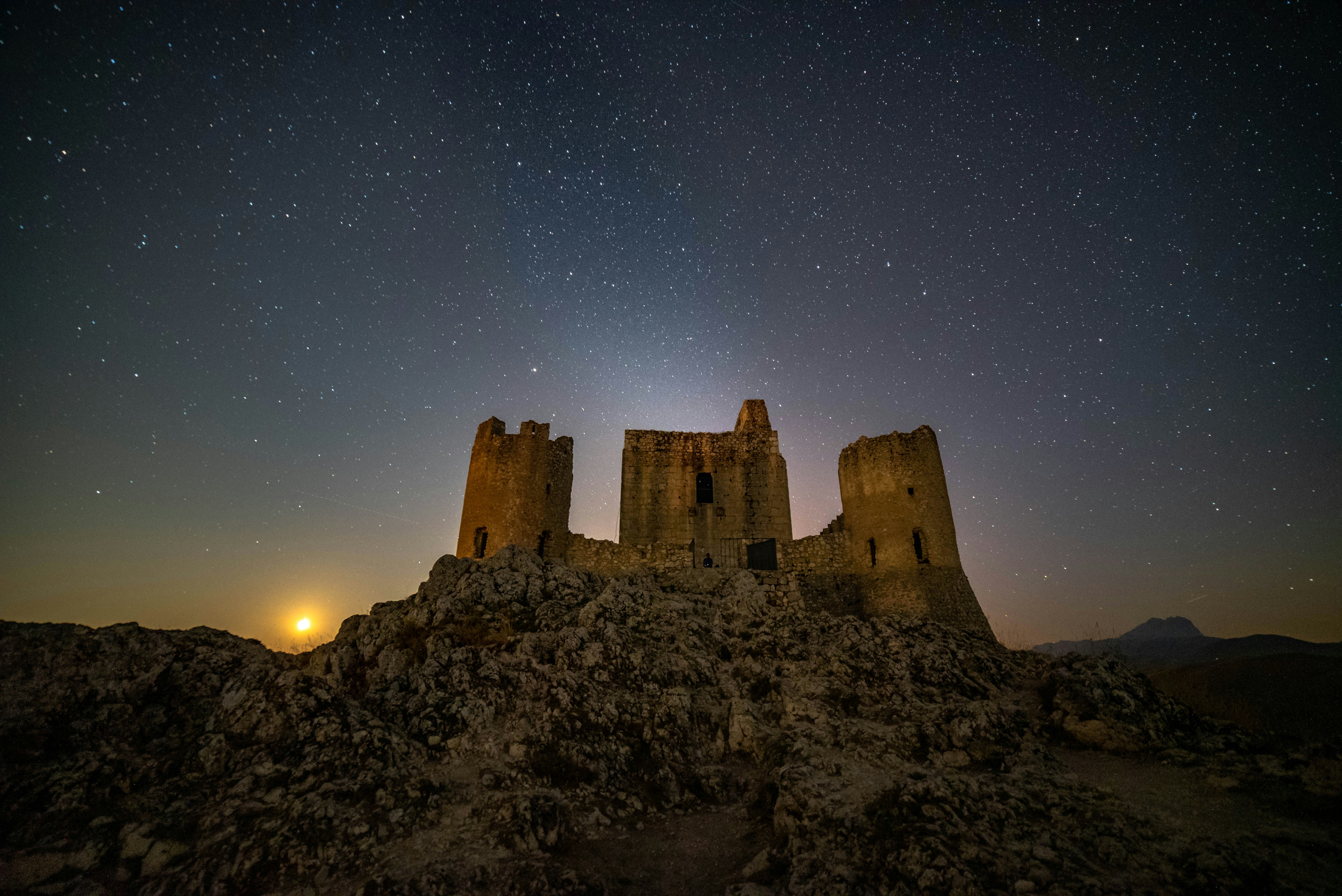 a castle on a rocky hill under a night sky