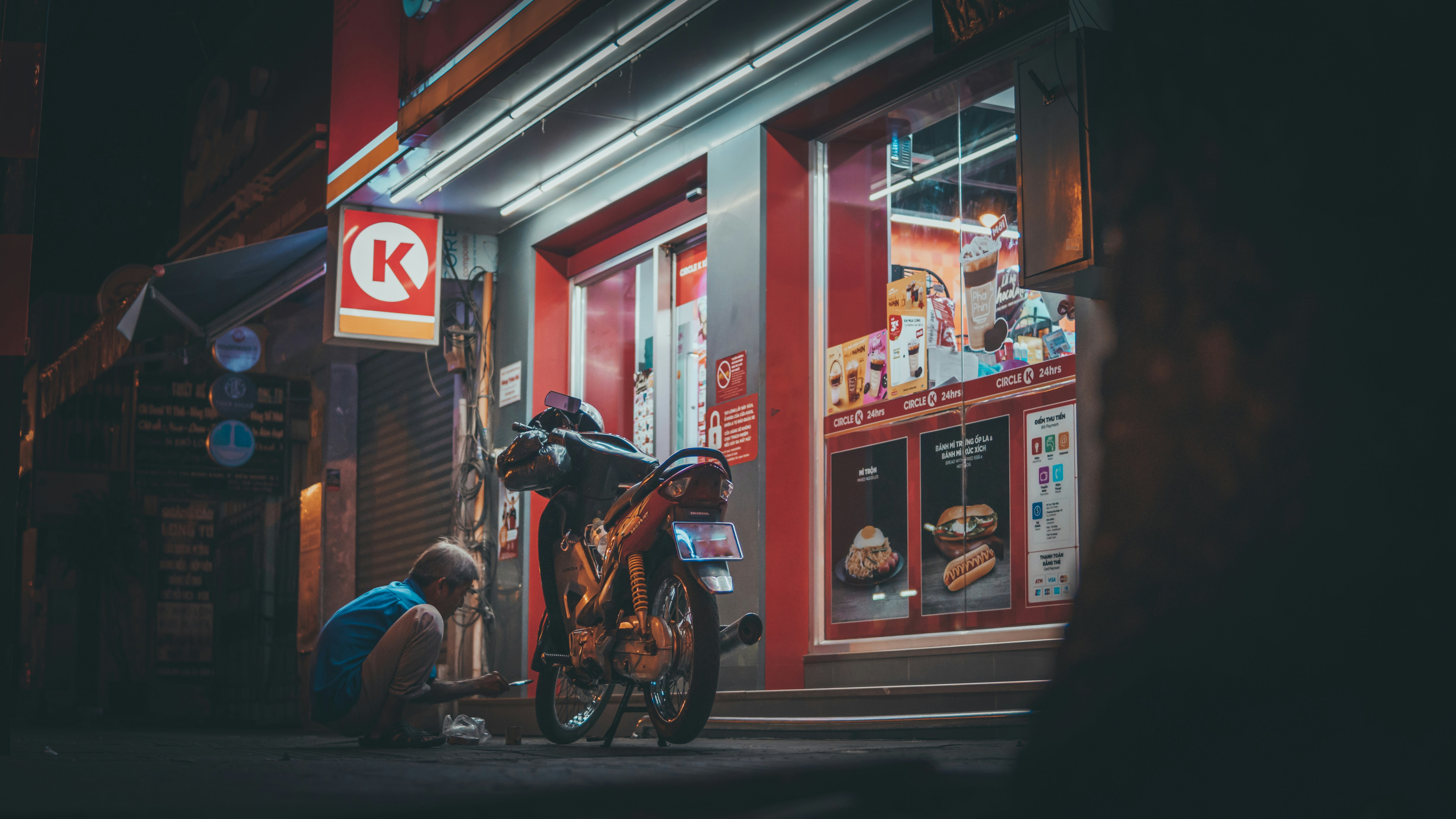 a man working on a motorcycle in front of a store