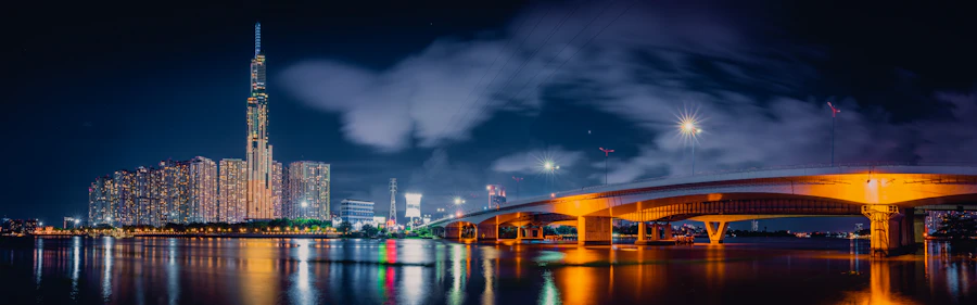 A bridge lit gold over water beside a city