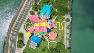 an aerial view of a colorful building next to the water