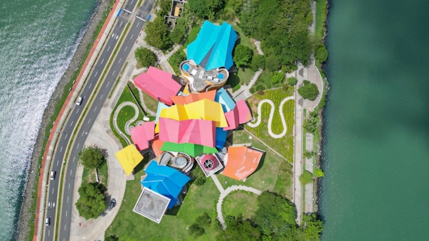 an aerial view of a colorful building next to the water