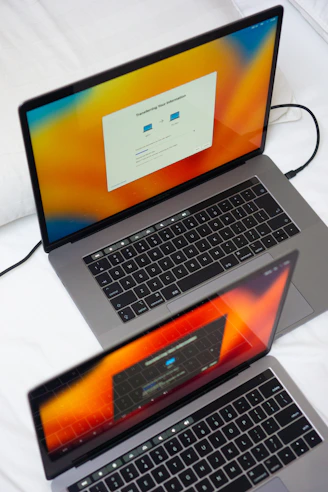 a couple of laptops sitting on top of a bed