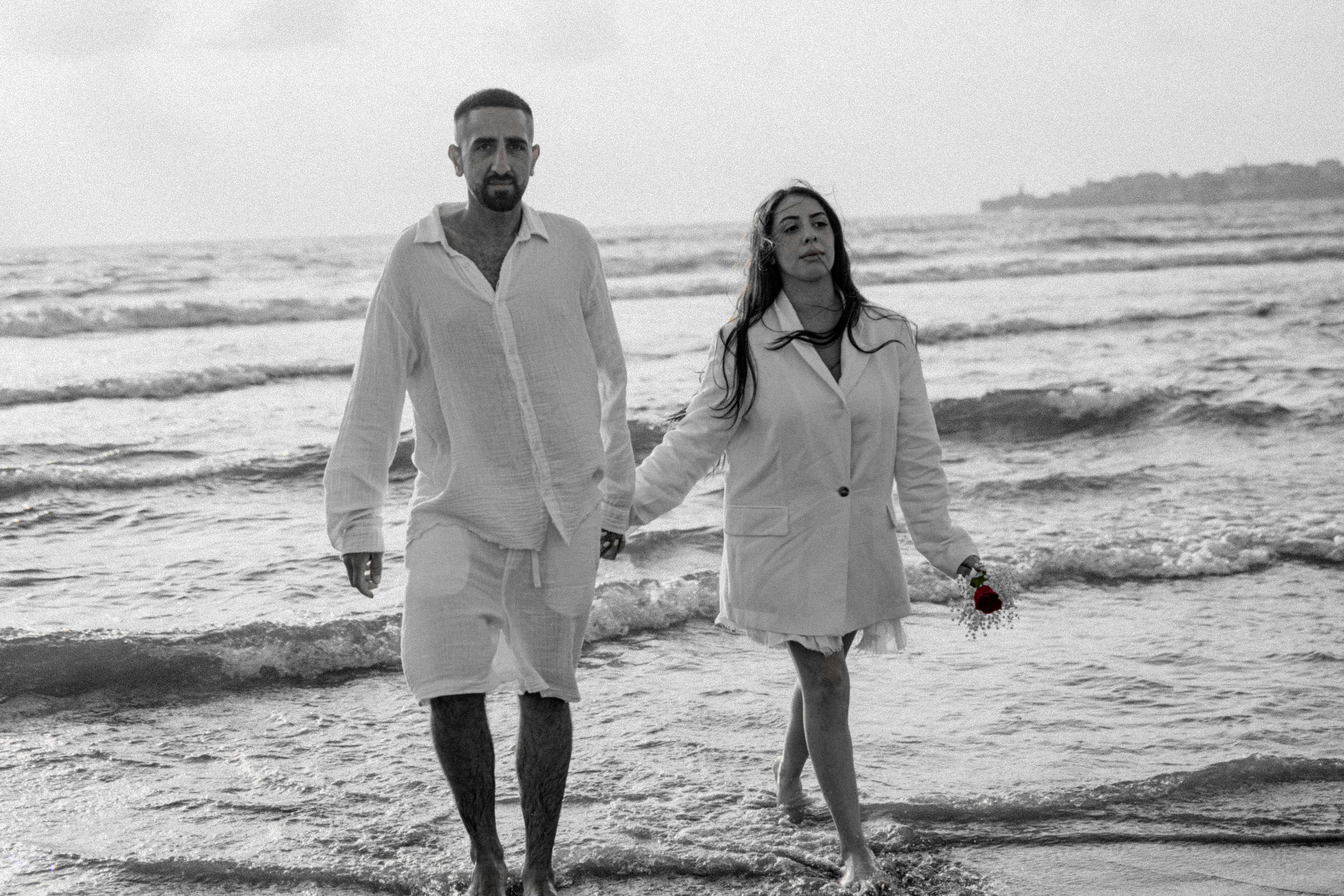 a man and a woman walking on the beach holding hands