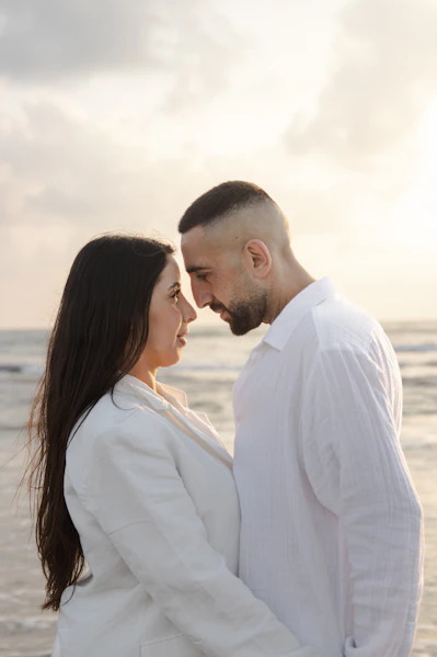 a man and woman standing on a beach next to the ocean