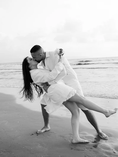 a man and woman kissing on the beach