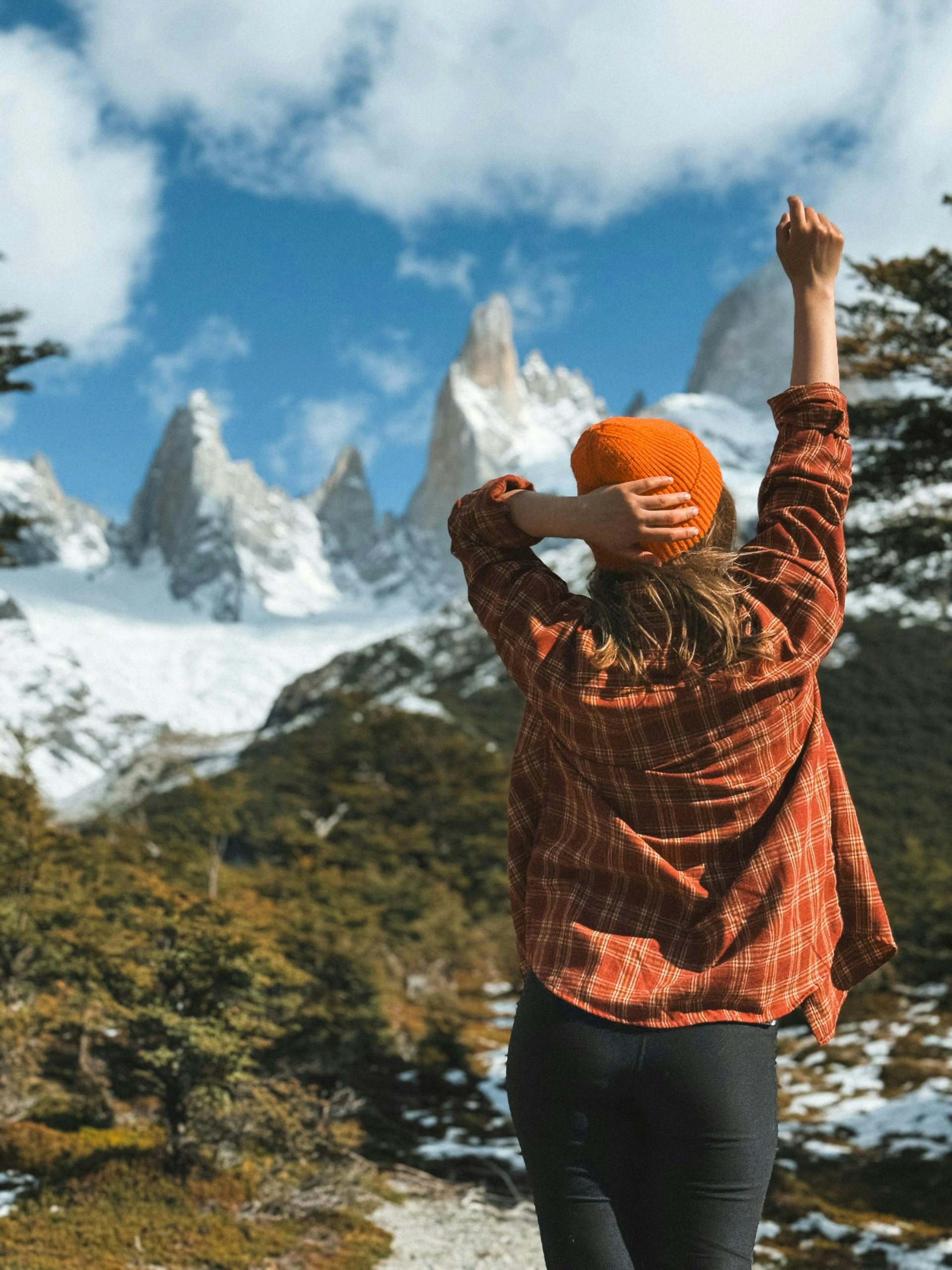 a woman with an orange hat standing on a mountain