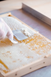 a person in white gloves is cutting a piece of bread