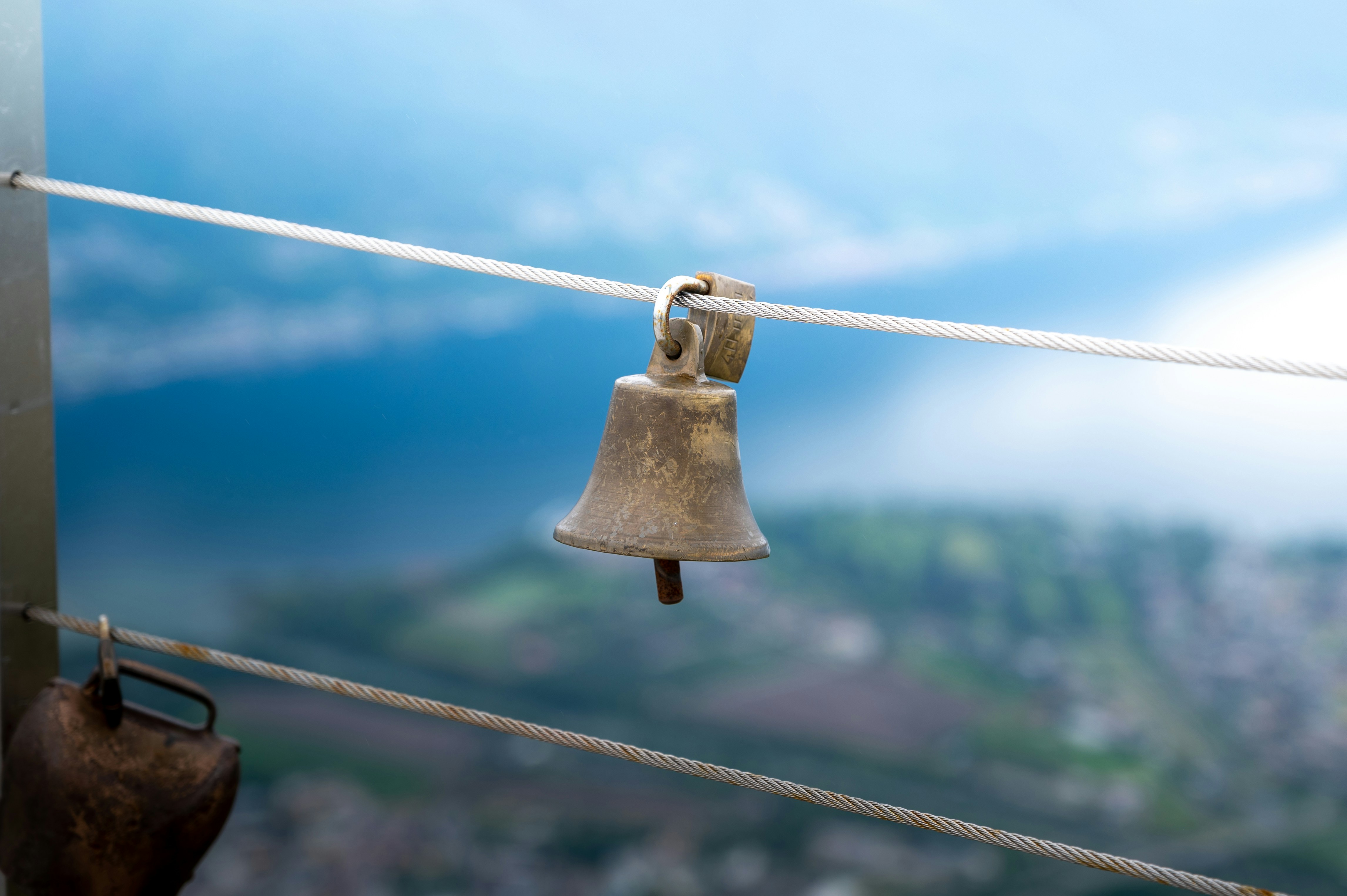 una campana colgada de una cuerda con una ciudad al fondo