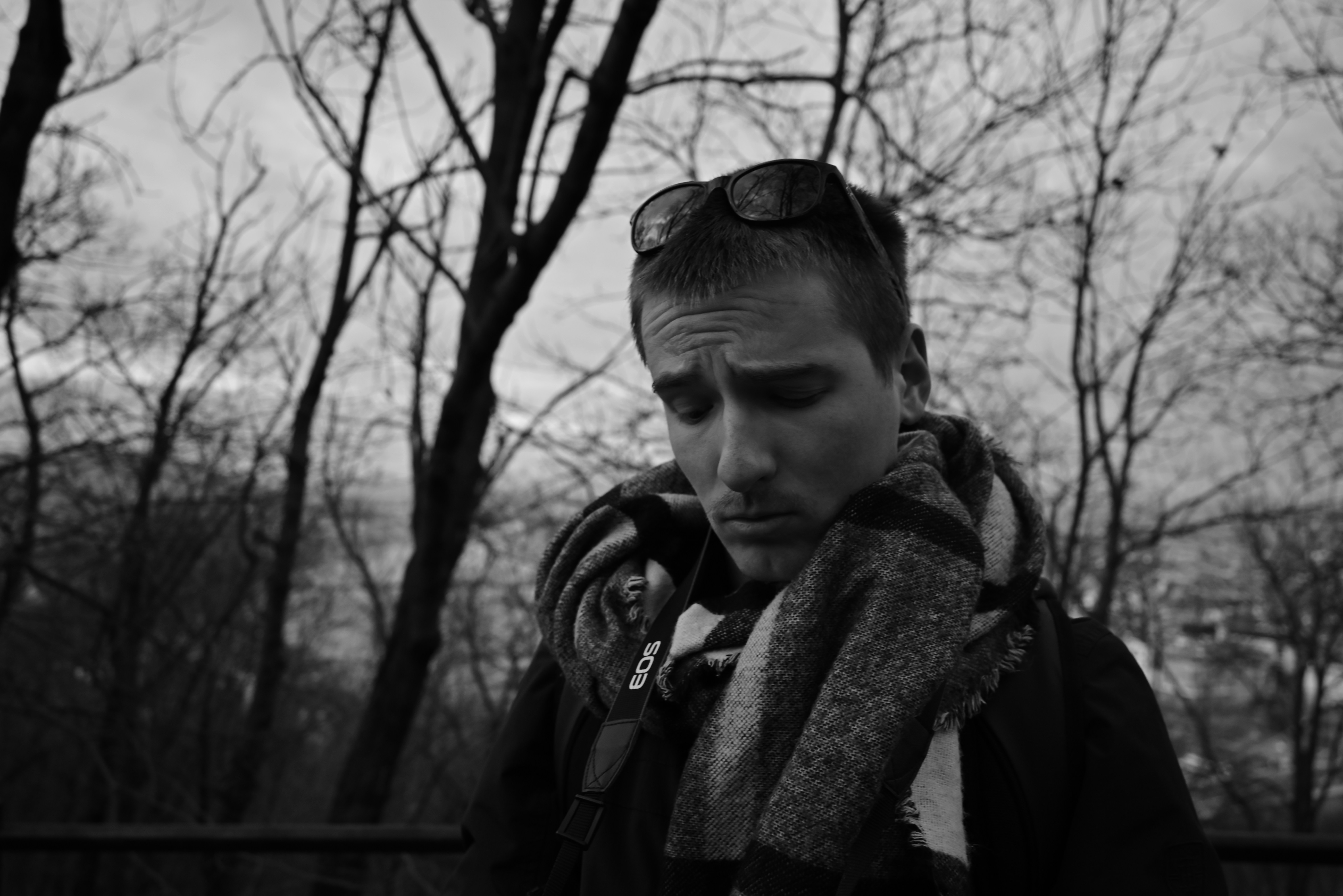 a man with a scarf around his neck looking at his cell phone