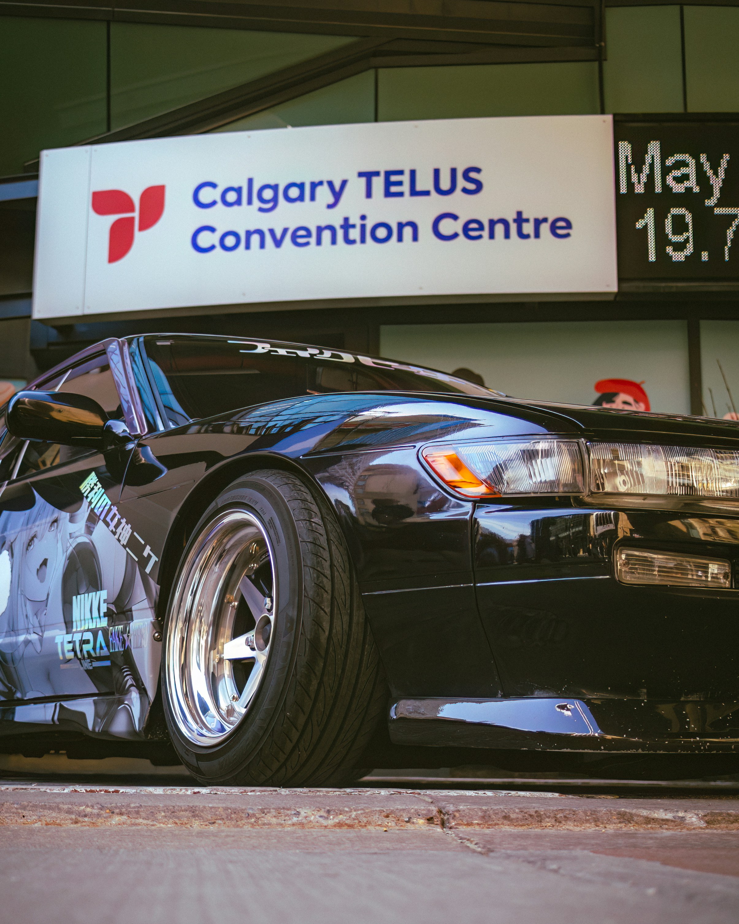A black sports car parked in front of a sign