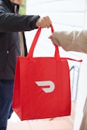 a person holding a red bag with the letter D on it
