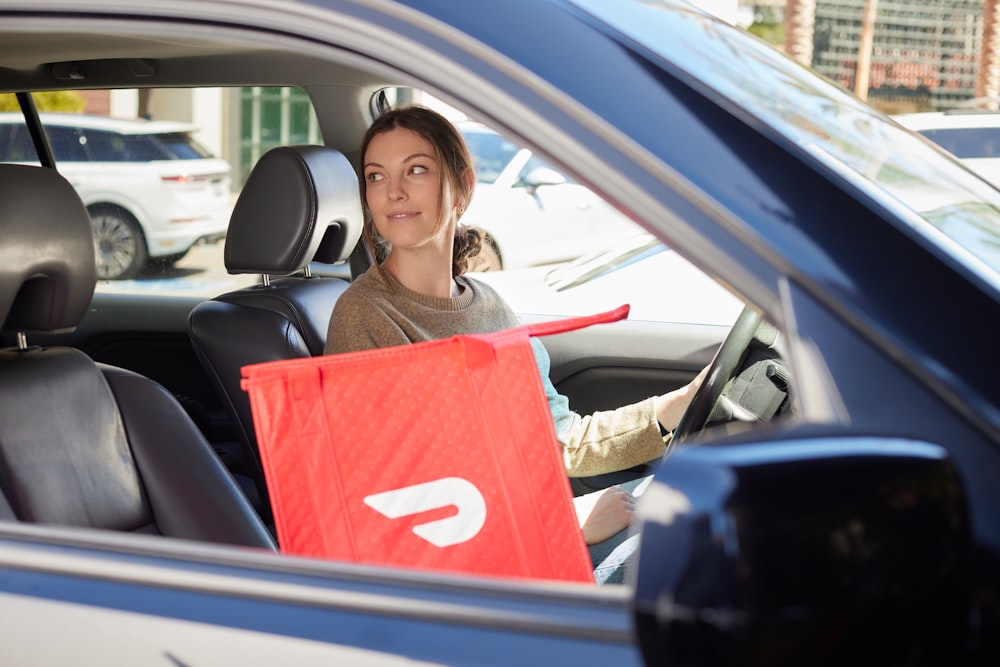 a woman sitting in a car with a shopping bag