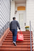 a man carrying a red shopping bag down a flight of stairs