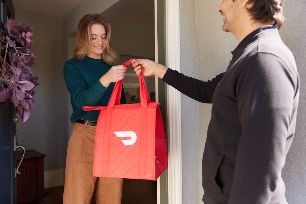 una mujer sosteniendo una bolsa de compras roja mientras está de pie junto a un hombre