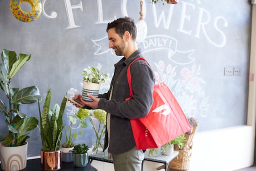 a man holding a potted plant in front of a chalkboard