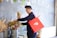 a man holding a red shopping bag near a bunch of flowers