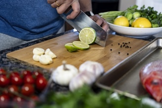 a person cutting a lime on a cutting board