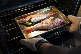 a person pulling a fish out of an oven