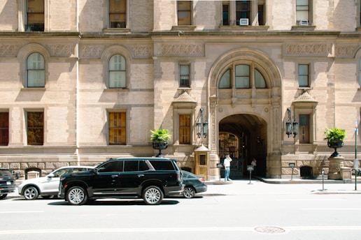 a black suv parked in front of a large building