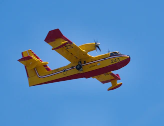 a yellow and red plane flying through a blue sky