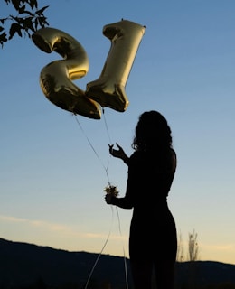 a woman holding a bunch of balloons in the shape of the letter e
