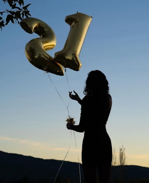 a woman holding a bunch of balloons in the shape of the letter e