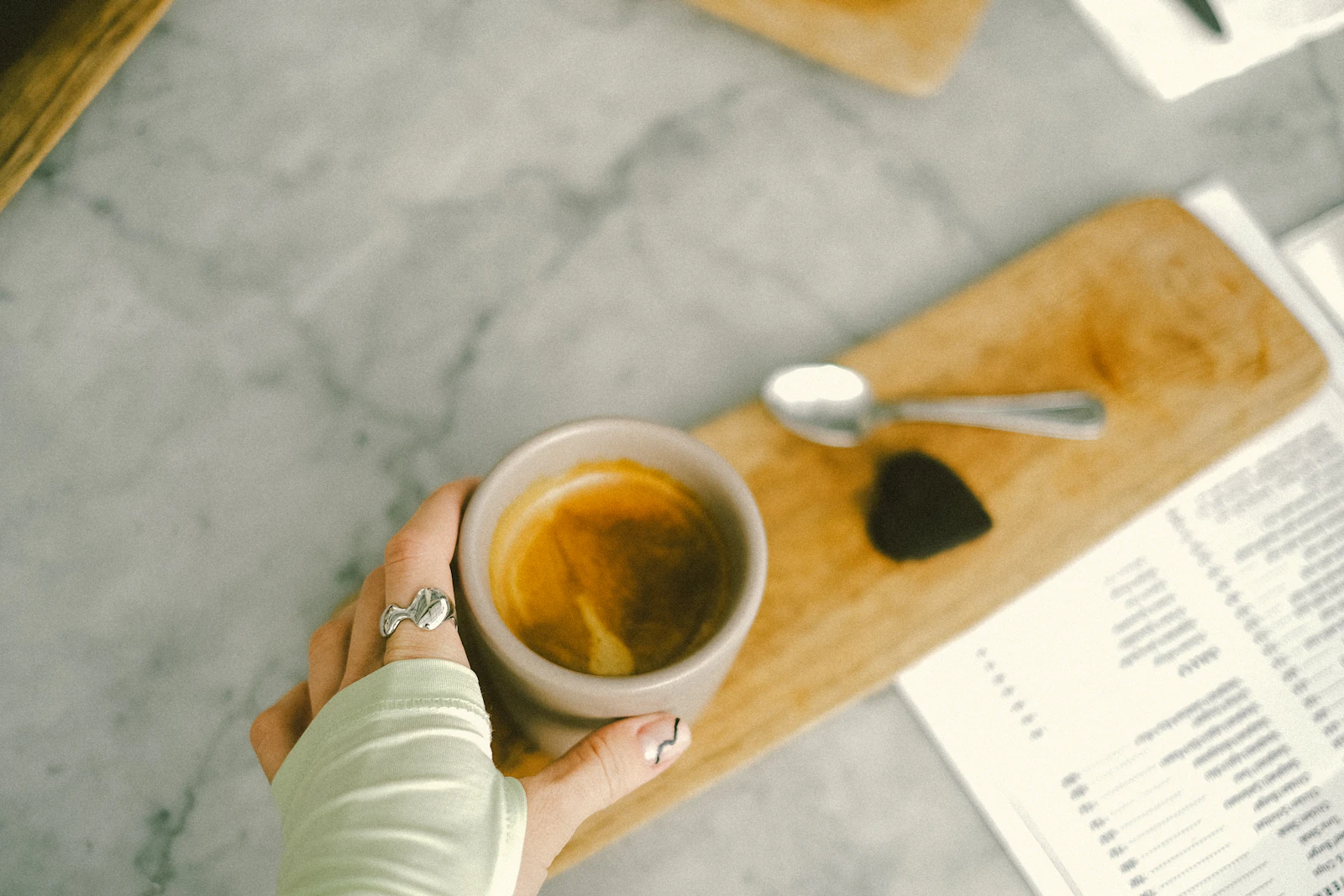 Eine Person hält eine Kaffeetasse an einem Tisch
