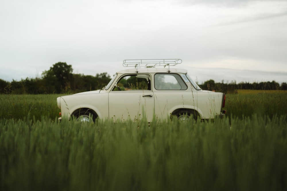 Un coche viejo está aparcado en un campo de hierba alta
