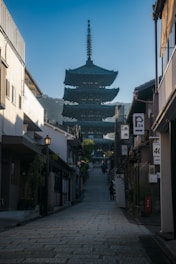 a narrow street with a pagoda in the background