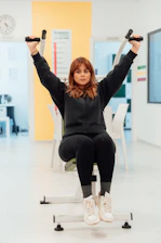 a woman sitting on a bench holding two dumbbells