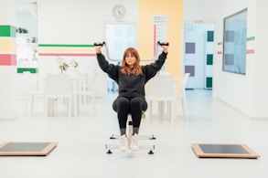 a woman is sitting on a chair with her hands in the air