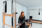 a woman standing in a gym holding a bar