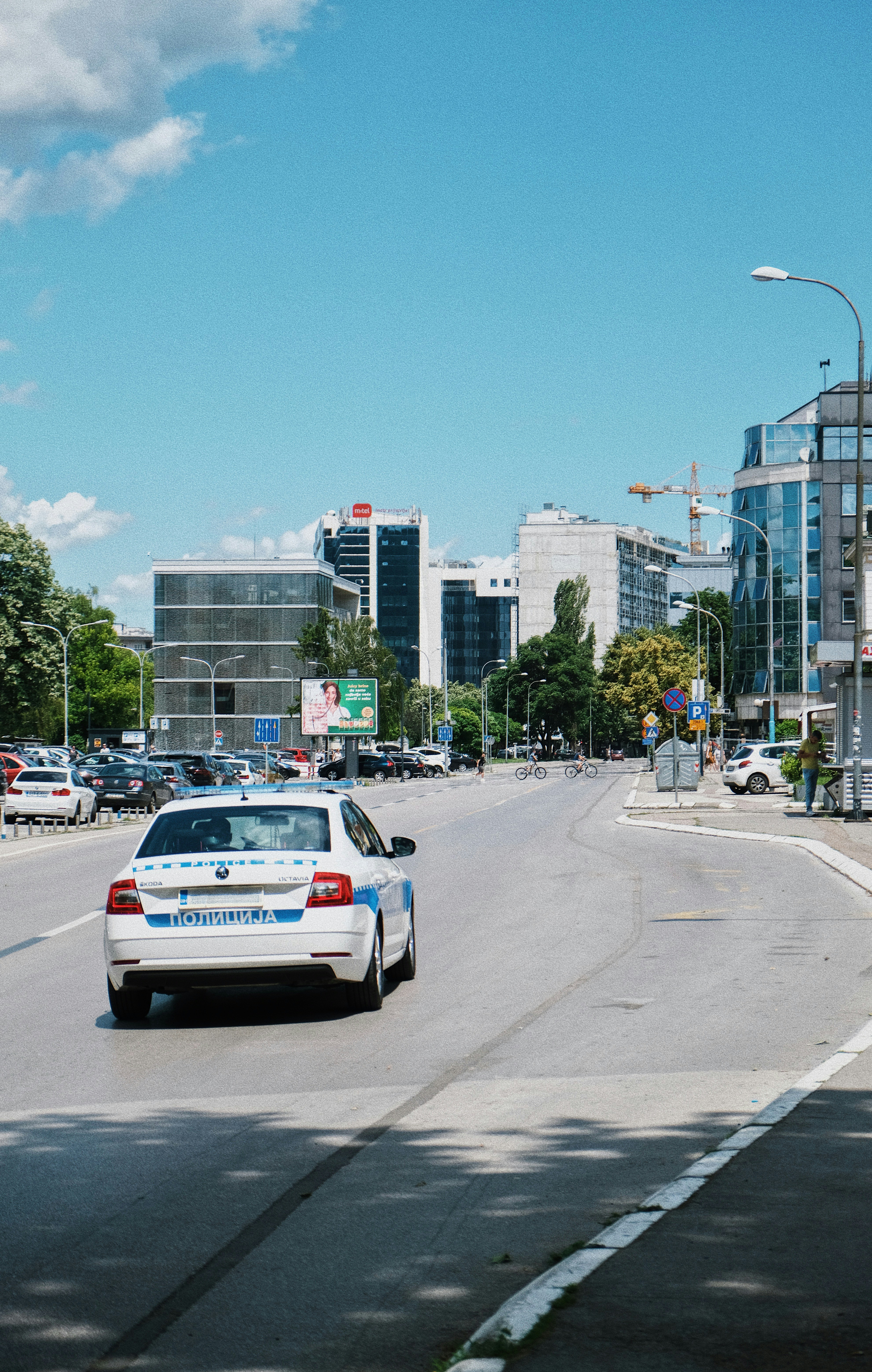 a white car driving down a street next to tall buildings