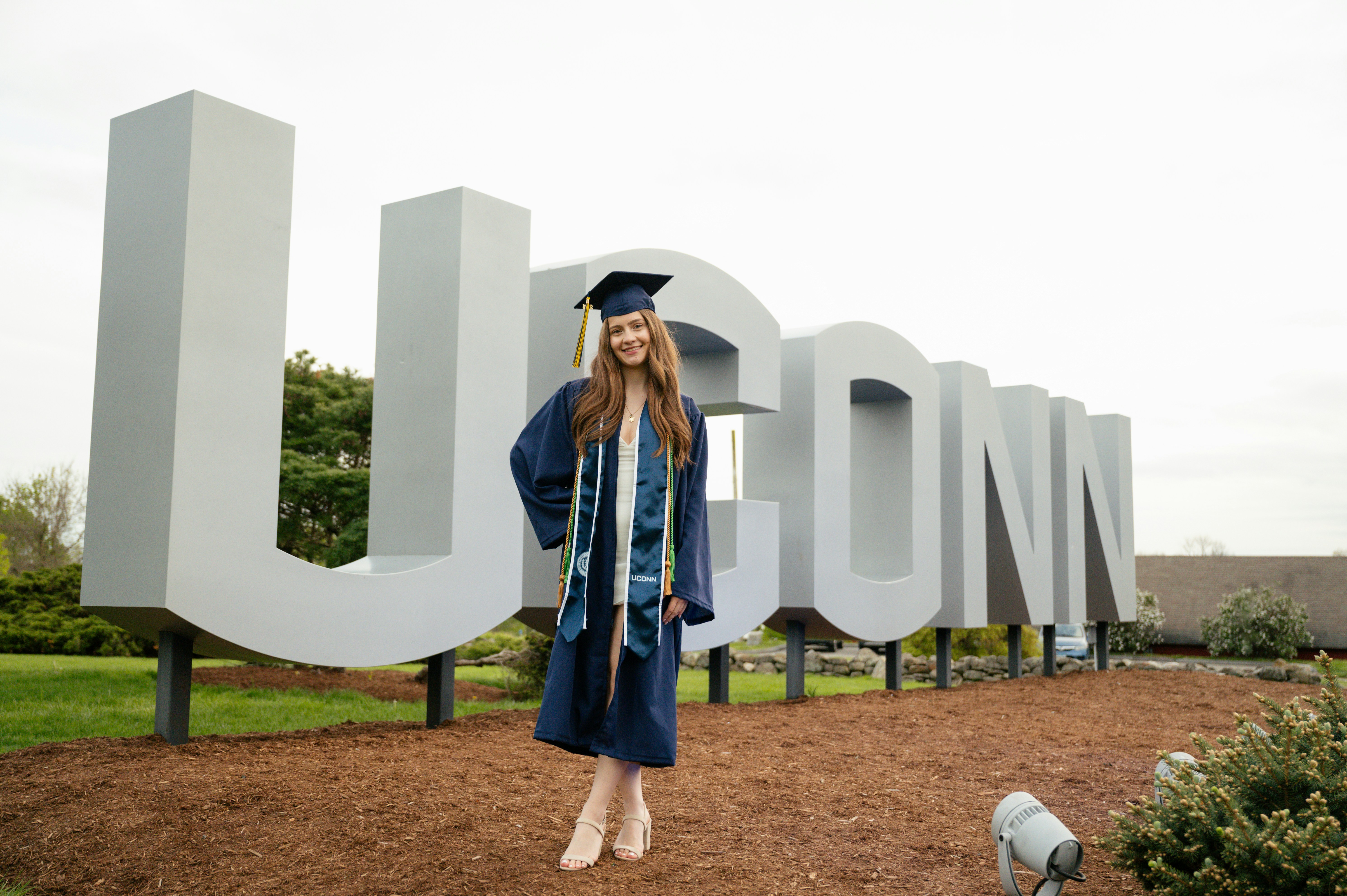 a woman in a cap and gown standing in front of a sign
