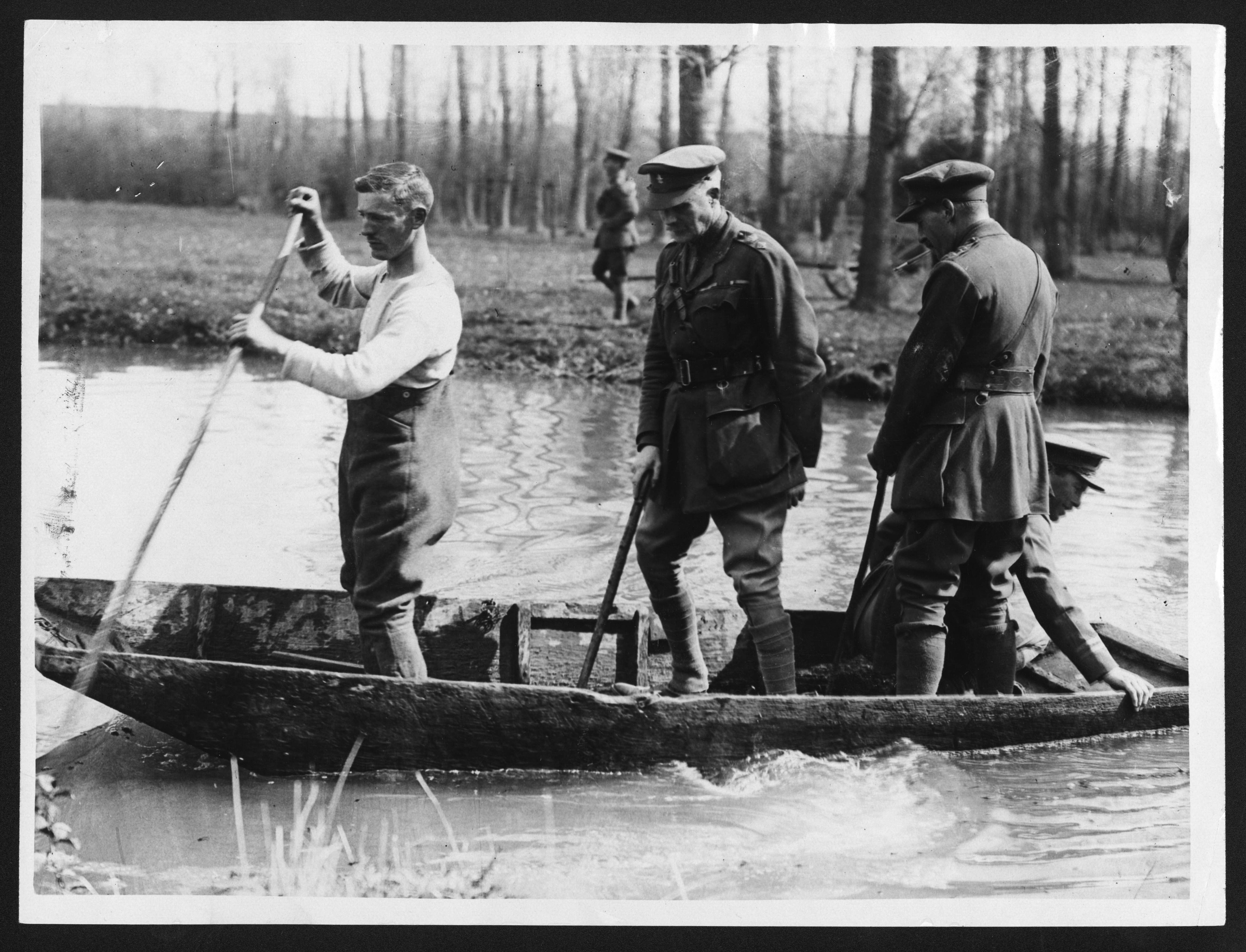 a black and white photo of men in a canoe
