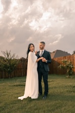 a newlywed man and a woman standing in the grass