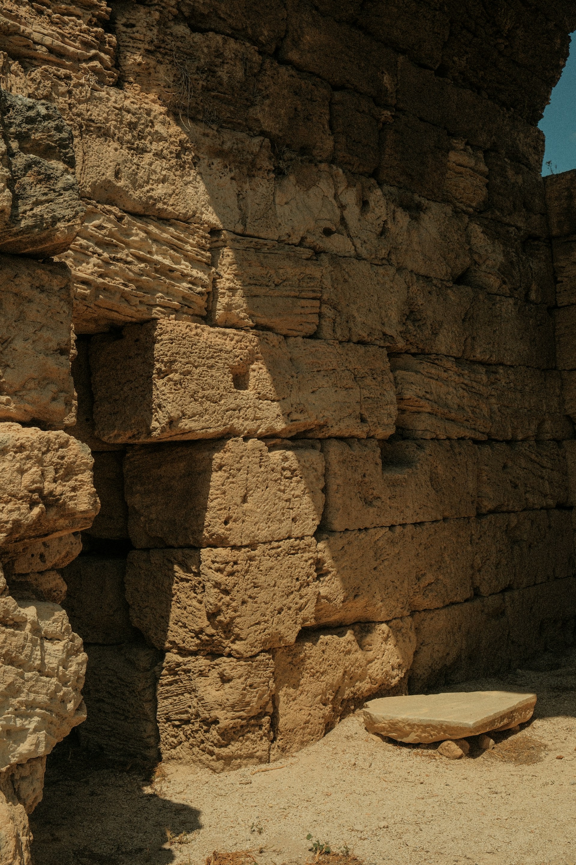 a stone bench sitting in front of a stone wall