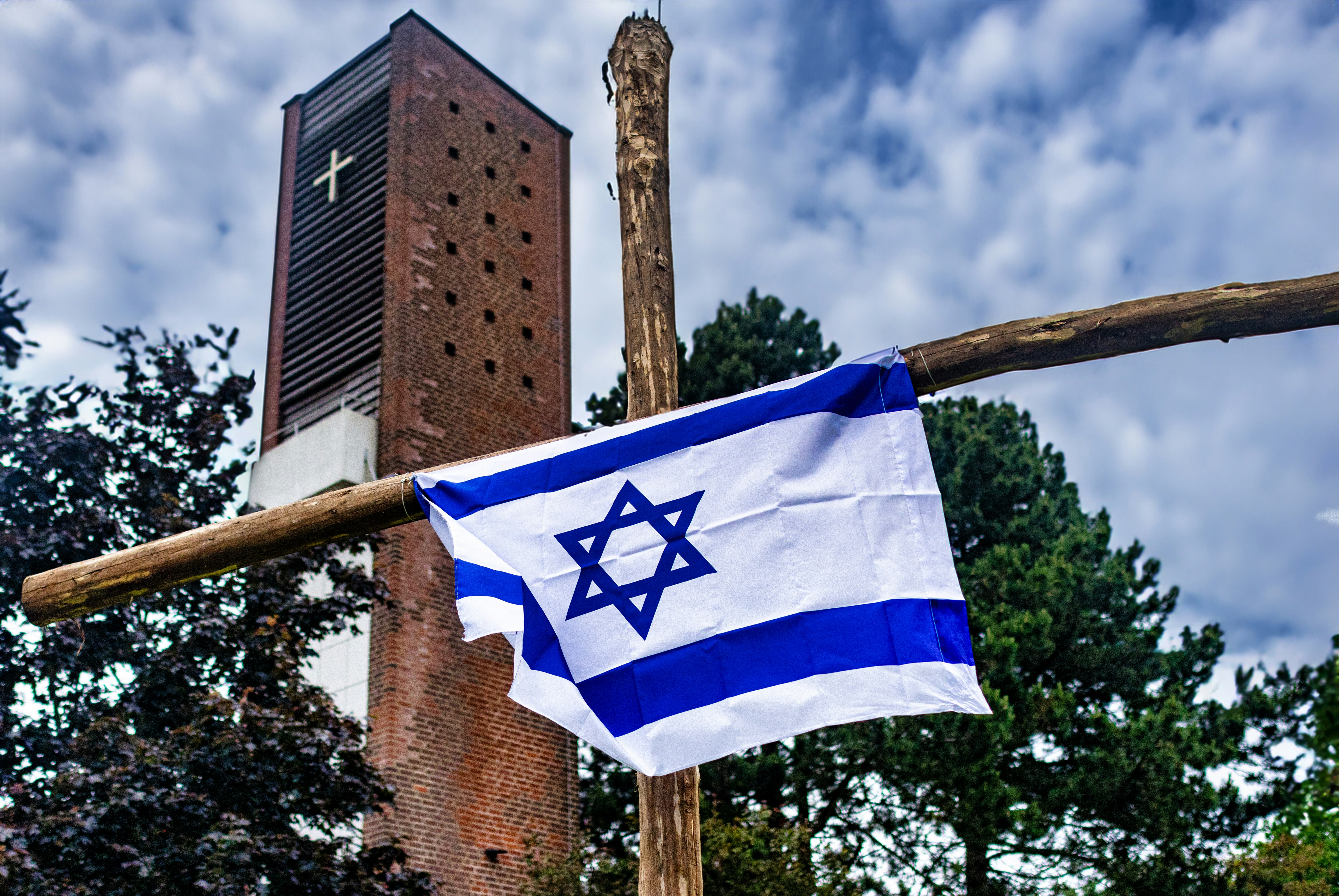 a flag hanging from a wooden pole in front of a tall building