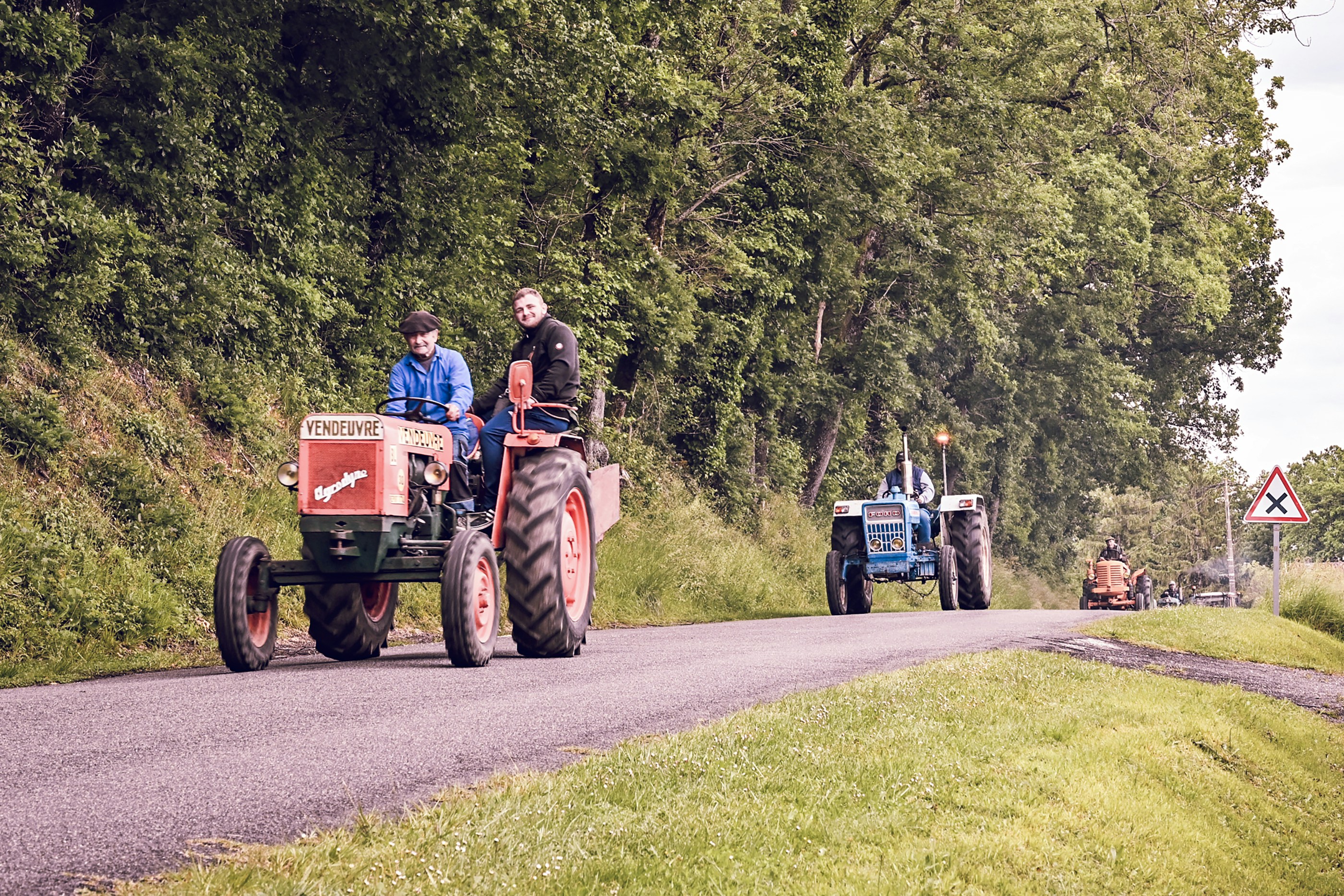 Agricultural tractor operating in citrus grove, professional equipment working through organized tree rows in Florida