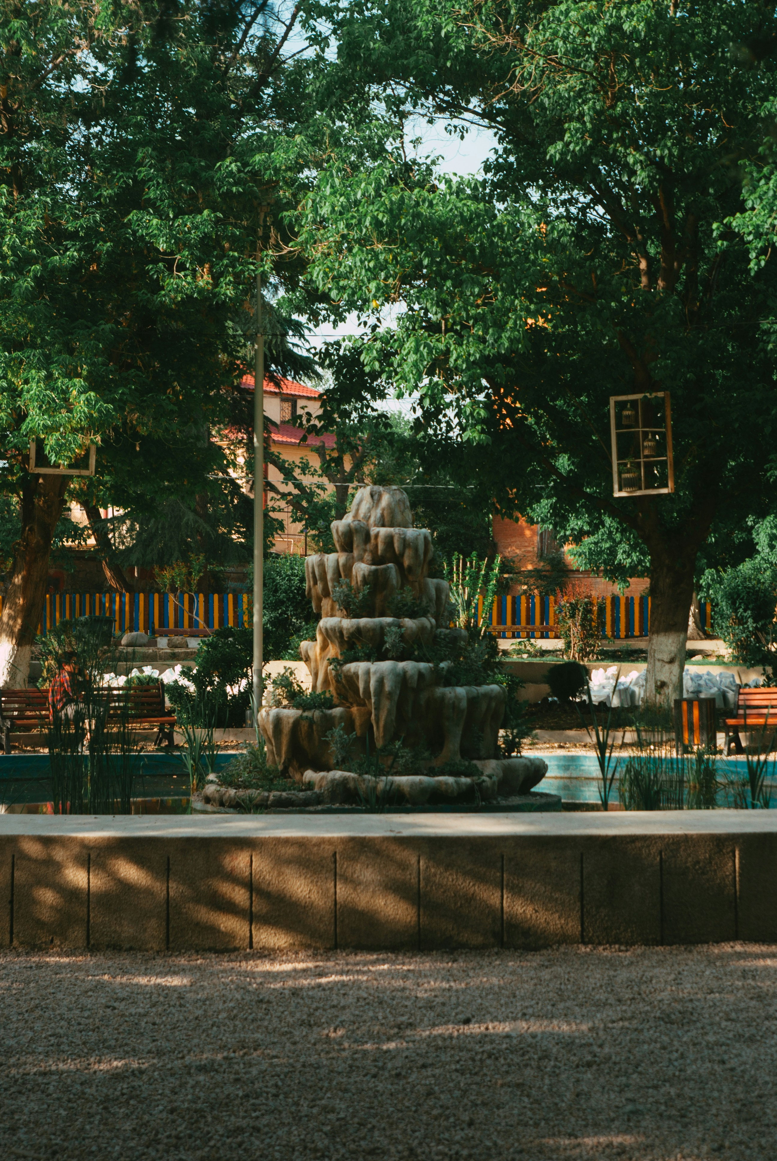 a fountain in a park with trees and benches
