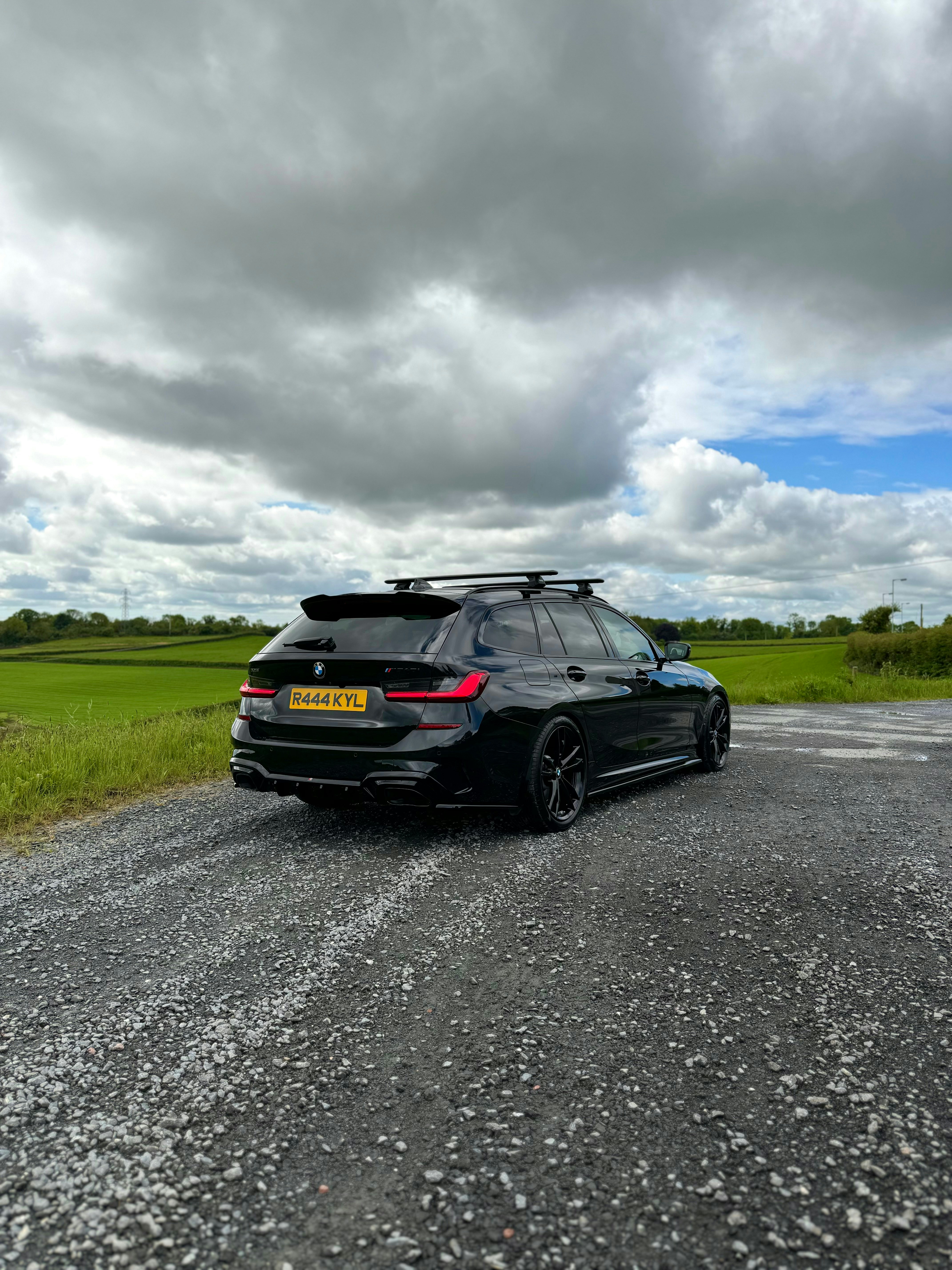a black car is parked on a gravel road